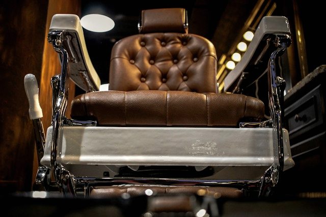 A vintage leather barber's chair under warm shop lighting.