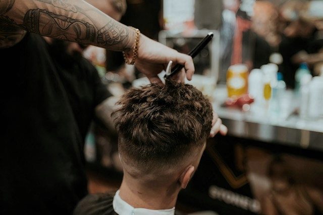 A barber working through a client's curls with scissors.