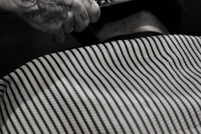 Detail of a striped barber cape and a freshly cut neckline.