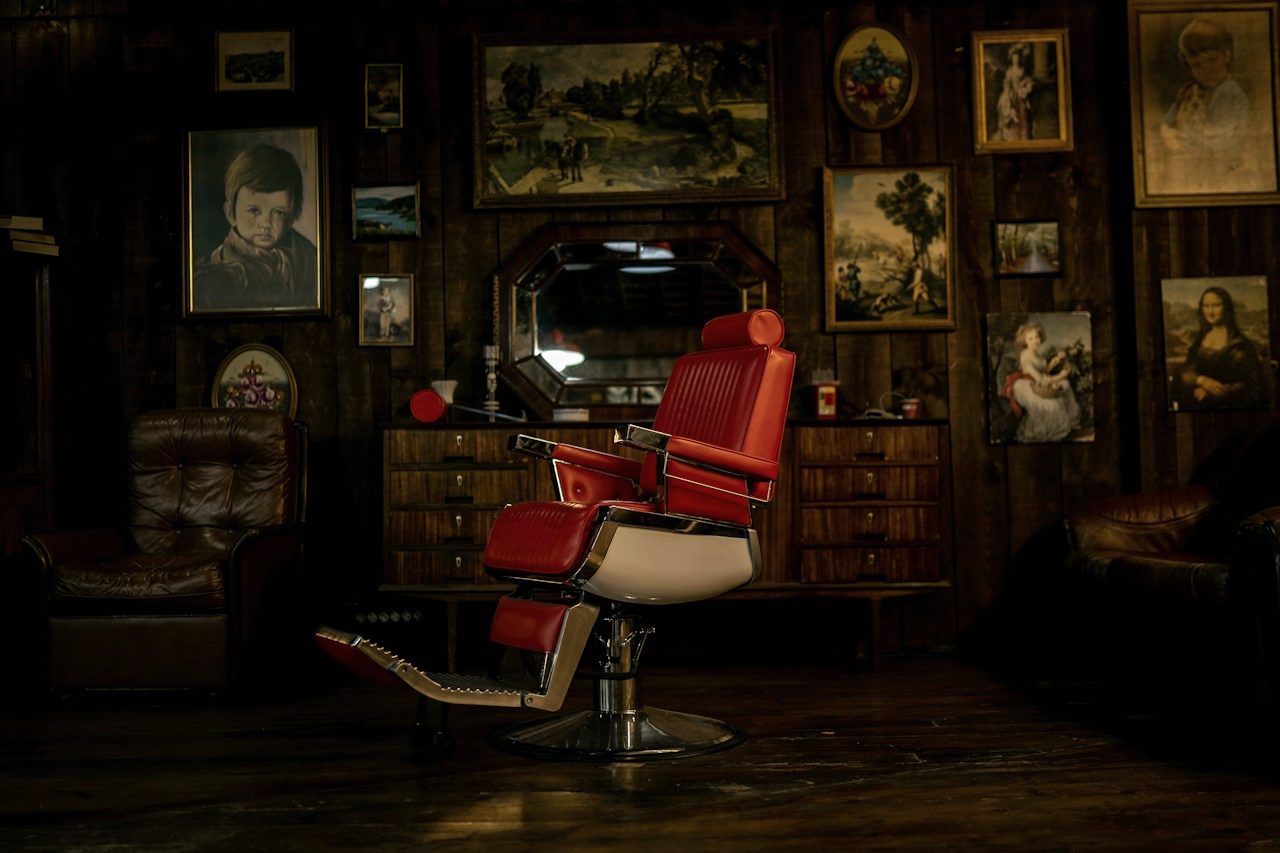 Inside the shop — a leather barber's chair framed by mirrors and framed prints.